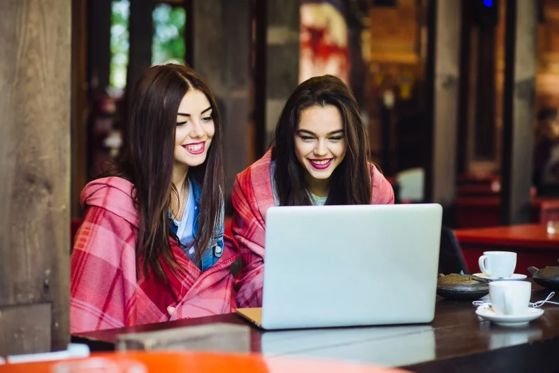 Two young women browsing internet on a laptop